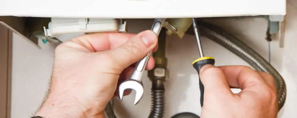 Boiler repair technician tightening pipe fittings and connections in Lexington, MA