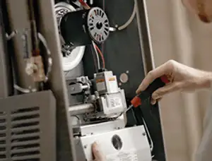 Furnace repair technician inspecting internal components and wiring in Lexington, MA