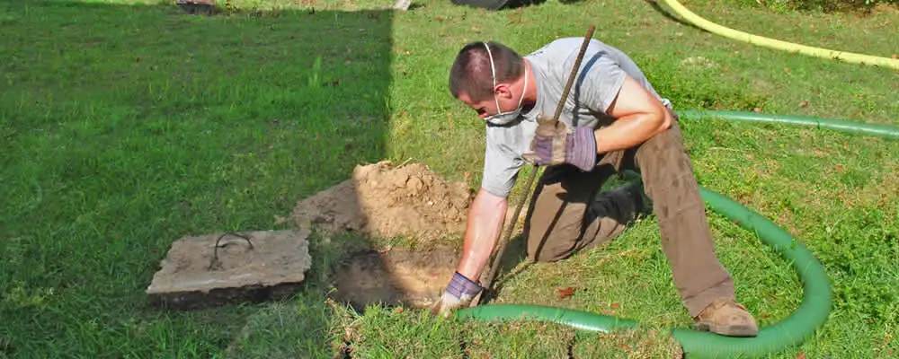 Septic pumping technician servicing a residential septic tank in Lexington, MA