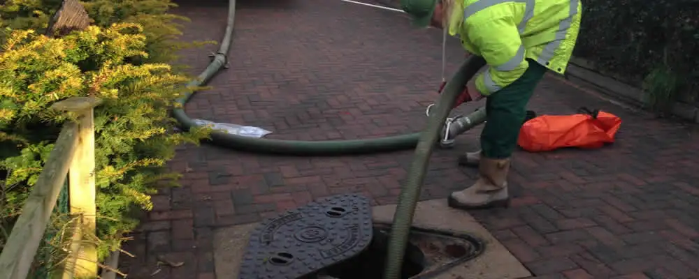 Septic tank cleaning technician servicing a septic tank with a vacuum hose in Lexington, MA