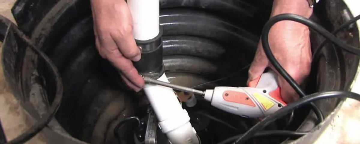 Sump pump installation technician connecting PVC discharge piping in Lexington, MA