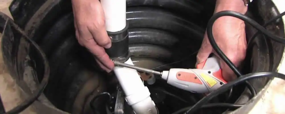 Sump pump installation technician connecting PVC discharge piping in Lexington, MA