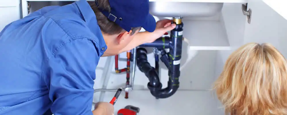 Plumber repairing under-sink drain pipes and fittings in Lexington, MA